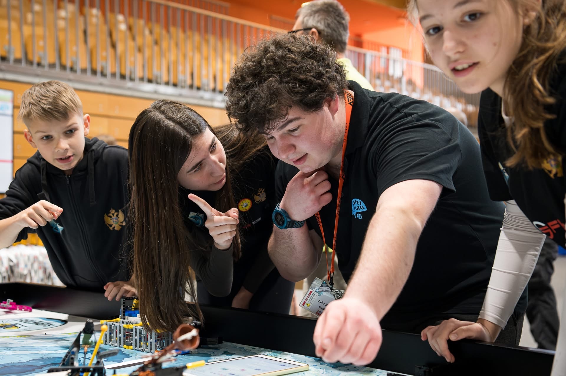 Team members leaning over the robot game table, following their robot's mission at a FIRST LEGO League competition